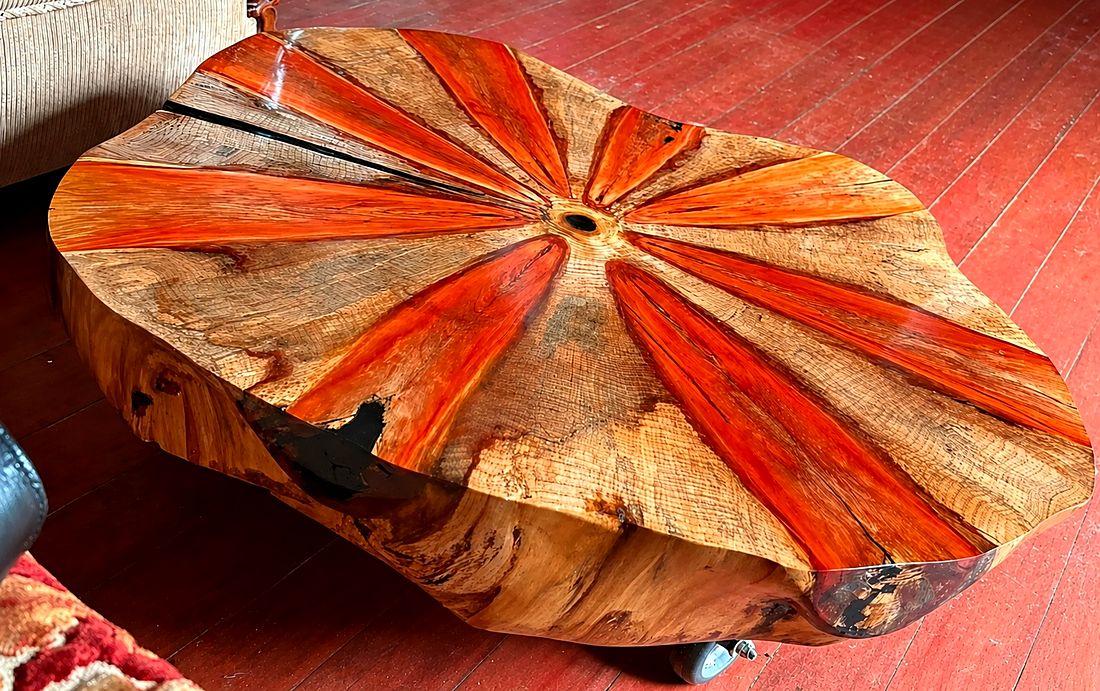Mesa de centro feita de uma bolacha de tronco, com veios alaranjados